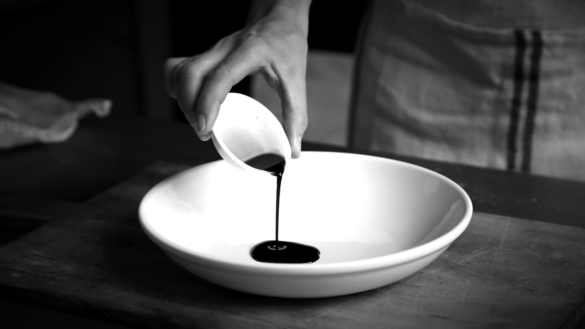 Mano che versa olio in un piatto